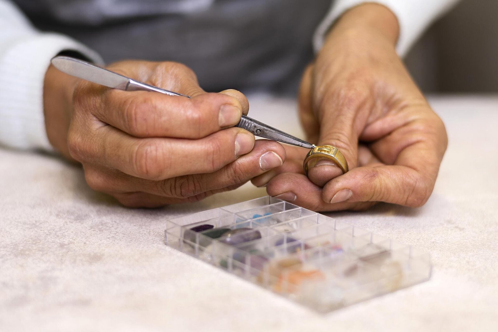 Avaliador utilizando uma ferramenta para inspecionar um anel de ouro detalhadamente.